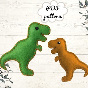 May include: Two felt dinosaur toys, one green and one orange, are shown against a white wood-grain background. The dinosaurs are stitched with contrasting thread. Text in a cloud bubble reads "PDF pattern".