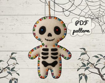 Könnte beinhalten: Ein Filz-Skelett-Ornament mit einem lächelnden Gesicht, schwarzen Augen und einer schwarzen Fliege. Das Skelett ist mit bunten Perlen an den Rändern und entlang des Brustkorbs verziert. Der Text "PDF pattern" befindet sich in einer Wolkenblase.