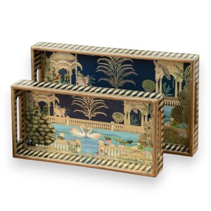 Puede incluir: Dos bandejas rectangulares decorativas con asas. Las bandejas presentan una ilustración detallada de una escena lacustre con cisnes, árboles y elementos arquitectónicos. Los bordes tienen un patrón de rayas negras y crema.