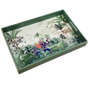 Puede incluir: Una bandeja rectangular con un marco de color verde intenso y asas integradas. La base presenta una ilustración detallada de un elefante azul adornado con patrones coloridos, rodeado de exuberante follaje tropical y un cenador blanco.