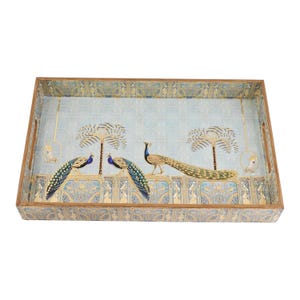 Op de afbeelding: Rechthoekig houten dienblad met een lichtblauwe achtergrond met een pauwenontwerp. De lade heeft gouden en blauwe accenten, met een gedetailleerde illustratie van pauwen, palmbomen en decoratieve randen. De lade heeft uitgesneden handgrepen.