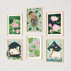Könnte beinhalten: Sechs gerahmte Kunstdrucke mit indisch inspirierten Illustrationen. Die Drucke zeigen Lotusblumen, ein Göttergesicht und Kühe, alles in leuchtenden Farben. Die Rahmen sind hellholzfarben, und der Hintergrund ist ein neutrales Weiß.