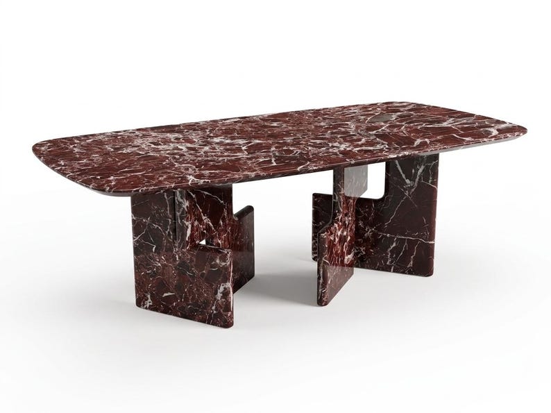 May include: A rectangular dining table with a red marble top and matching base. The table has rounded corners and a unique leg design. The marble features white veining throughout.