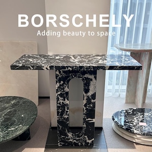 May include: A black and white marble table with a rectangular top and a matching base. The table is surrounded by other marble tables. The text "BORSCHELY Adding beauty to space" is at the top of the image. The table is likely around 120 cm long.