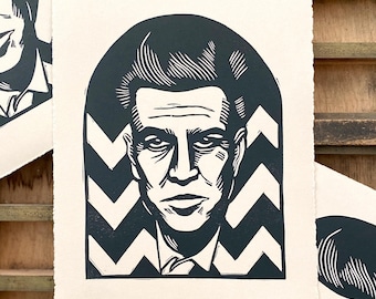 May include: Black and white linocut print of a man's face with a black and white chevron pattern in the background.