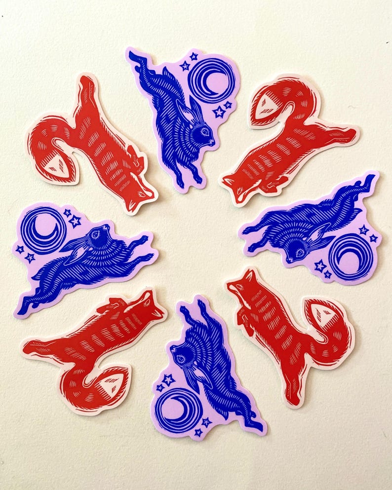 Puede incluir: Un conjunto de pegatinas con zorros rojos y conejos azules en poses din&aacute;micas. Cada pegatina tiene un dise&ntilde;o &uacute;nico, con un fondo lila claro que incluye una luna creciente y estrellas. Las pegatinas est&aacute;n dispuestas en un patr&oacute;n circular.