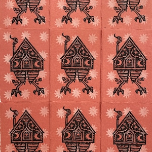 May include: Nine black and white illustrations of a house with a chimney and eyes, standing on two legs with feet. The house has a crescent moon and stars on the front. The background is a light pink with white stars.