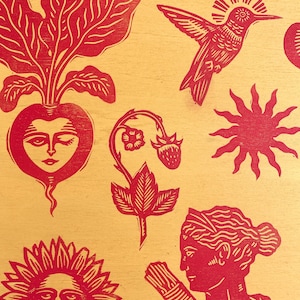 May include: Red linocut print on a yellow background featuring various botanical and celestial elements. Includes a radish with a face, a hummingbird, a sun, a strawberry plant, a sunflower, and a woman with a bundle.