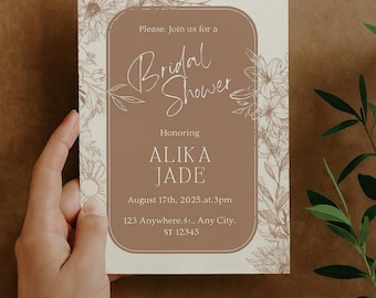 May include: A bridal shower invitation with a floral design. The invitation features the words "Bridal Shower" in elegant script, along with the honoree's name, date, time, and address. The color scheme is a soft brown and cream.