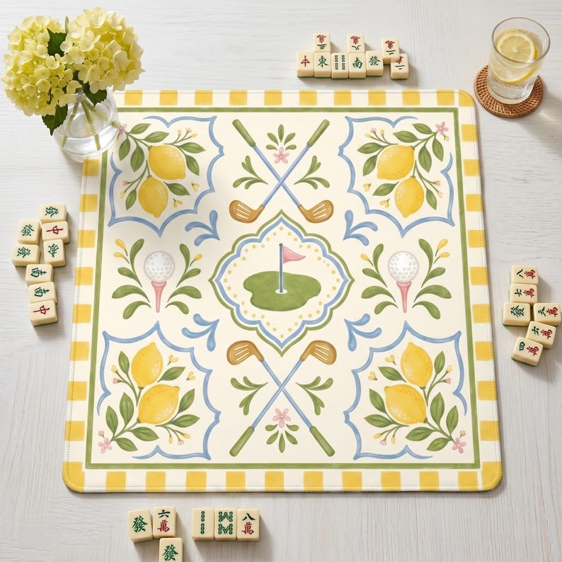 May include: A decorative square mat with a golf and lemon design. The mat features crossed golf clubs, golf balls on tees, and a golf green with a flag. Lemons and floral accents are also present. The border is yellow and white checkered.