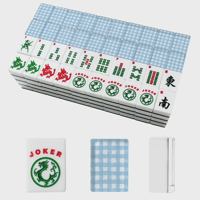 May include: A complete Mahjong set with white tiles featuring green and red dragon designs, numbers, and Chinese characters. The set includes blue and white checkered card-like pieces and a single "JOKER" tile with a green dragon.