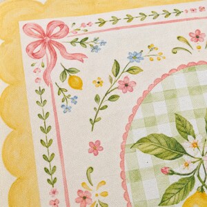 Pode incluir: Close-up de um tecido decorativo com um design de lim&atilde;o e floral. O tecido apresenta uma borda amarela ondulada, um la&ccedil;o rosa e um padr&atilde;o xadrez verde e branco. O design inclui lim&otilde;es, flores e folhas.
