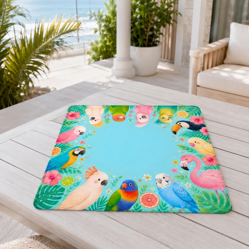 May include: A rectangular mat with a vibrant tropical bird design. The mat features a light blue center surrounded by colorful parrots, flamingos, and tropical flowers. The mat is placed on a light-colored wooden table.