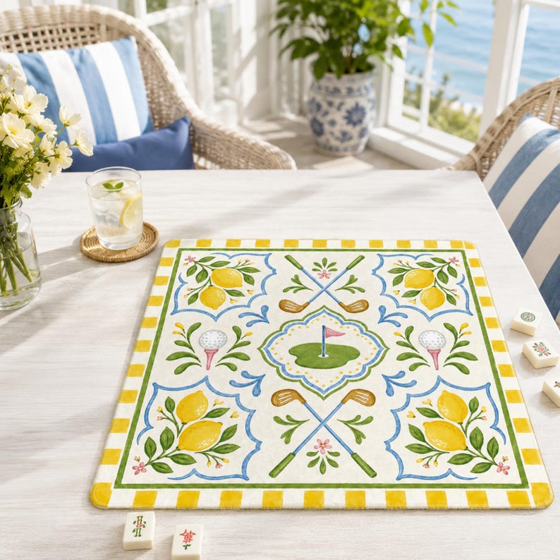 May include: A rectangular placemat with a golf and lemon design. The placemat features a cream background with yellow and green borders. The design includes lemons, golf clubs, golf balls, and a green golf course with a pink flag.