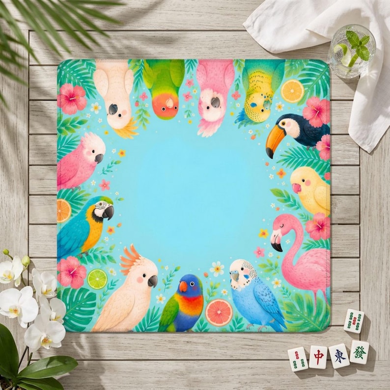 May include: A square, colorful mat featuring a variety of cartoon parrots, a toucan, and a flamingo around a light blue center. Tropical flowers and fruit decorate the border. The mat is on a wooden surface.