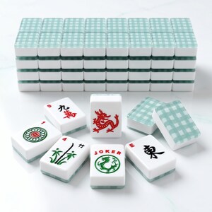 May include: A complete Mahjong set with white tiles featuring various symbols and characters in red and green. The tops of the tiles have a light blue and white checkered pattern. The set includes a stack of tiles and several individual tiles.