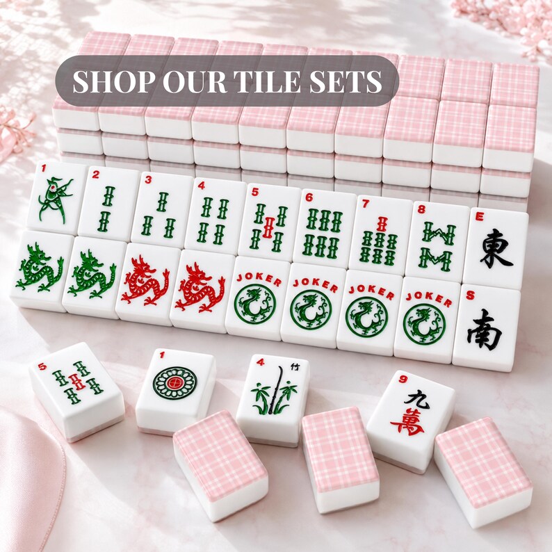 Pode incluir: Um conjunto de pe&ccedil;as de Mahjong brancas com v&aacute;rios s&iacute;mbolos e n&uacute;meros, incluindo drag&otilde;es e Jokers. As pe&ccedil;as s&atilde;o dispostas com conjuntos de pe&ccedil;as estampadas em rosa e branco no fundo. O texto "SHOP OUR TILE SETS" &eacute; exibido no topo.