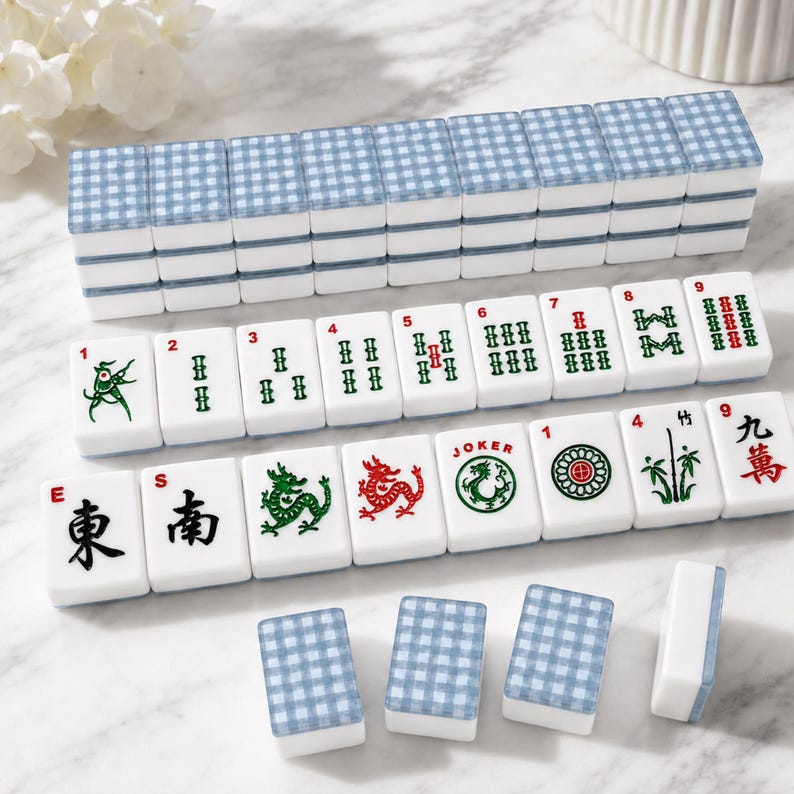 May include: A Mahjong set with white tiles featuring various symbols, numbers, and Chinese characters. The tiles have a blue and white checkered pattern on the back. The set includes tiles with dragons, bamboo, and other traditional designs.