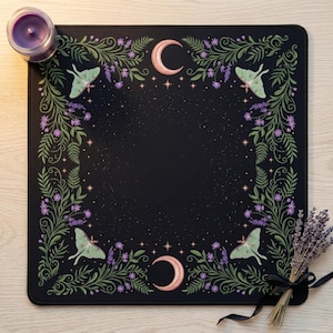 May include: A square black mat featuring a border of green fern leaves, purple flowers, and four light green moths. The design includes two peach-colored crescent moons at the top and bottom, surrounded by small white stars on a dark background.