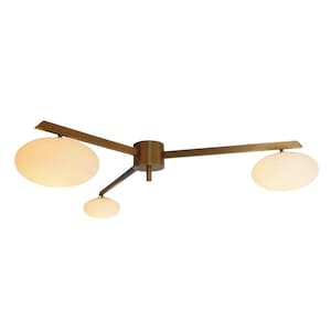 May include: A modern ceiling light fixture with a brass finish. It features three arms extending from a central hub, each holding an oval-shaped, frosted glass shade. The light fixture is designed for overhead illumination.