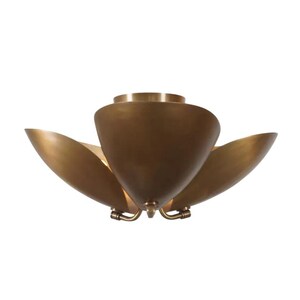 May include: A brass-colored ceiling light fixture with a flower-like design. The fixture has three large, curved petals and a central cone-shaped element. The light is mounted on a white background.