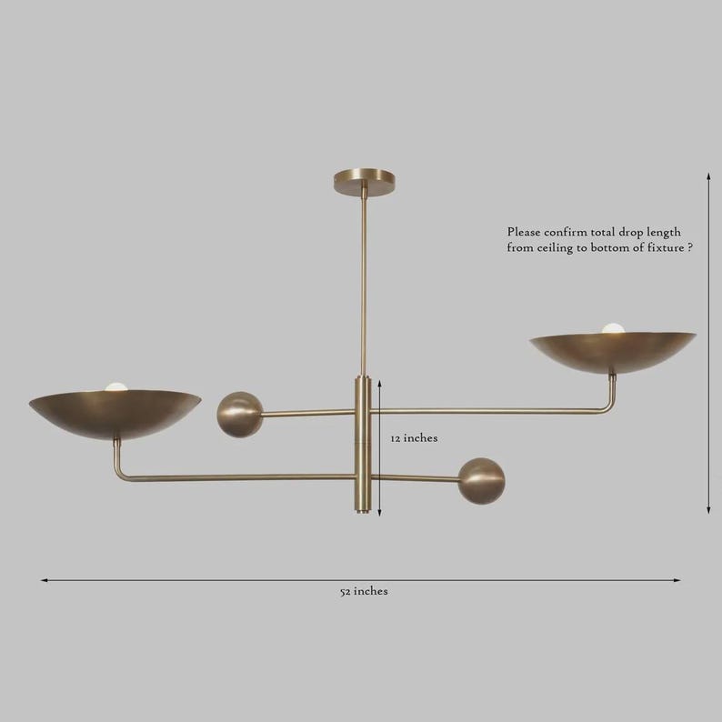 May include: A brass-toned chandelier with a modern design. The fixture has a 52-inch width and a 12-inch drop. It features two bowl-shaped shades and three spherical accents. The text in the image asks to confirm the total drop length.