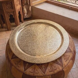 "Engraved brass tray hanging on a white wall as a piece of statement art."