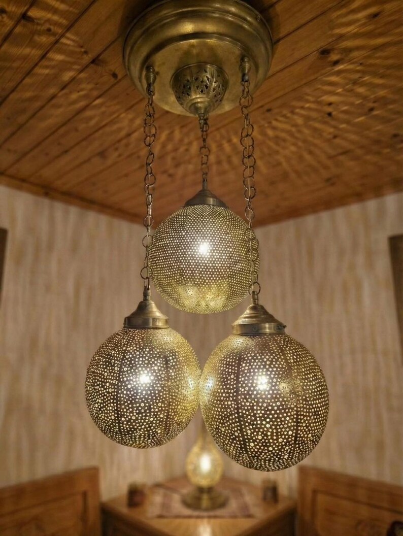 Handmade brass ceiling light hanging over a wooden dining table in a boho living room.