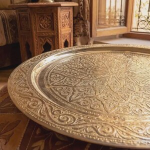 "Artisan's hands polishing a traditional Moroccan brass tray in a workshop."