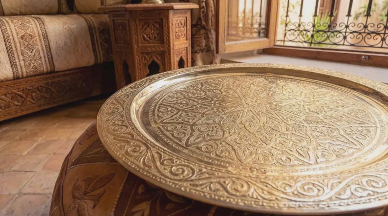 "Artisan's hands polishing a traditional Moroccan brass tray in a workshop."