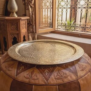 "Top-down view of a golden brass tray with a Moroccan tea set and mint."
