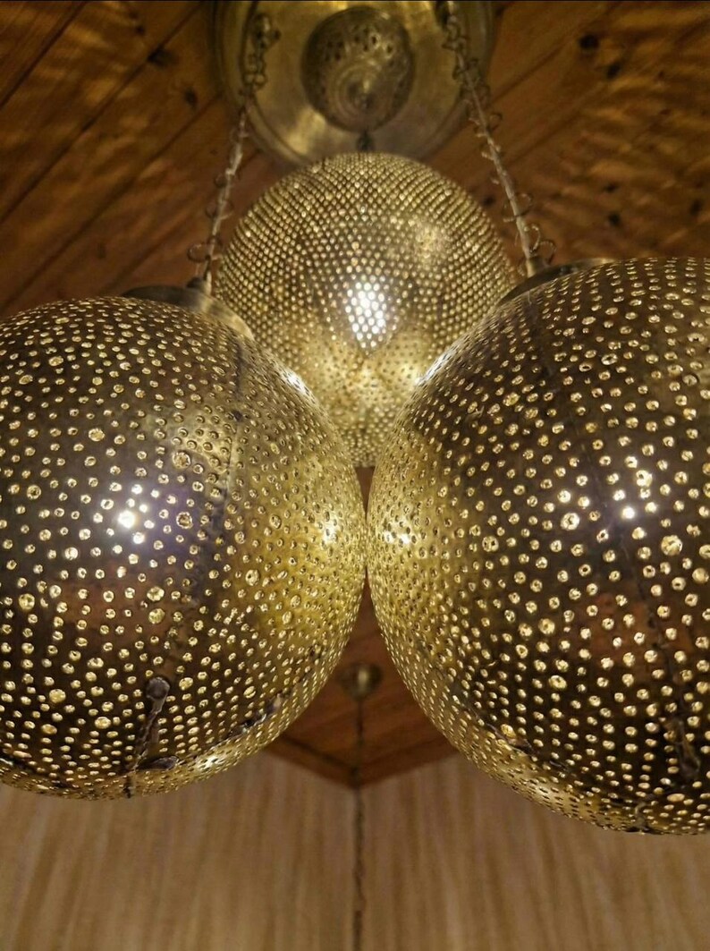 Moroccan globe lamp lit up casting beautiful shadow patterns on white walls.