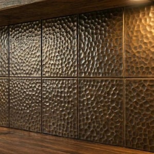 Könnte beinhalten: Bronze farbene, strukturierte Wandfliesen mit gehämmertem Metall-Aussehen. Die Fliesen sind in einem Raster angeordnet und reflektieren das Licht von Deckenleuchten. Die Fliesen sind über einer Holzoberfläche montiert.