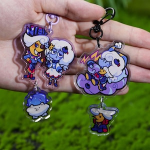 Può includere: Una collezione di portachiavi in acrilico trasparente con personaggi dei cartoni animati. I portachiavi mostrano personaggi in varie pose, con colori vivaci e la parola "NIGHT" visibile su uno. Ogni portachiavi ha un fermaglio in metallo.