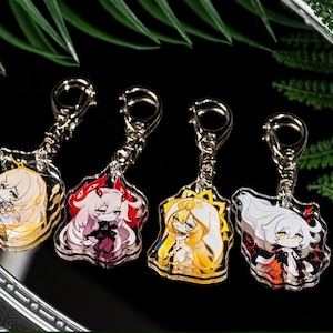 Puede incluir: Cuatro llaveros de personajes de estilo anime con anillos plateados. Cada llavero presenta un diseño de personaje diferente con varios colores de cabello, incluyendo rubio, rosa y blanco, y atuendos detallados. Los llaveros están hechos de acrílico transparente.
