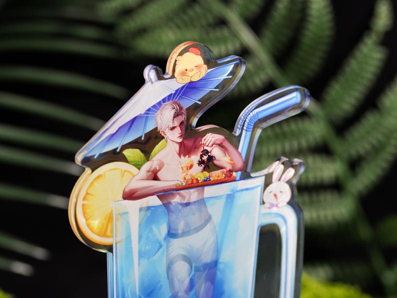 May include: A clear acrylic charm featuring a male anime character in a blue drink. The character is holding a tray of fruit. A lemon slice, a small Winnie the Pooh, and a bunny are also featured.