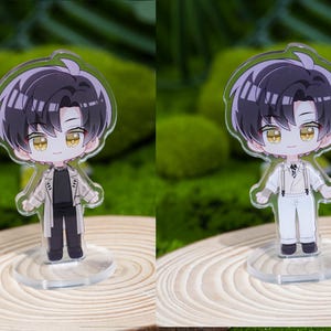May include: Two acrylic anime-style figurines of a male character with black hair and yellow eyes. One figure wears a black outfit with a tan coat, the other wears a white outfit with suspenders. Both stand on clear bases.