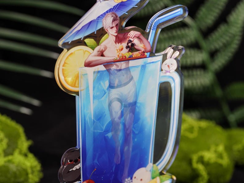 May include: A clear acrylic charm in the shape of a large glass of blue liquid with a straw. The charm features a shirtless man standing in the glass, holding a tray of food. A lemon slice, a small umbrella, and cartoon characters are also included.