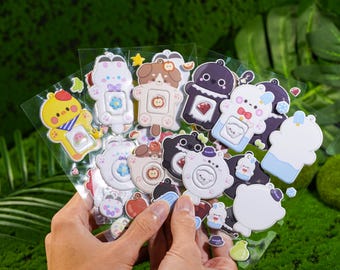 May include: A collection of colorful, cartoon-style stickers featuring various animal characters. The stickers are in various shapes and sizes, with a variety of colors, including yellow, white, brown, and black. The stickers are held in a person's hands.