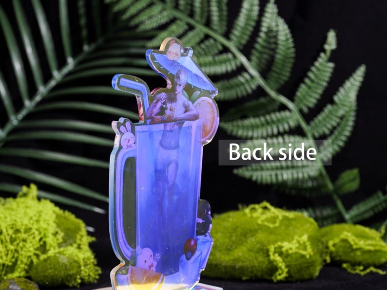 May include: A clear acrylic figure of a cocktail with a mermaid design. The drink has a blue hue, a straw, and a lemon slice. The words "Back side" are visible on the right side of the figure.