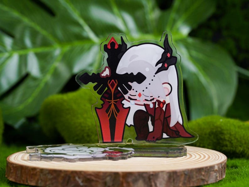 K&ouml;nnte beinhalten: Ein klarer Acryl-Charm mit einer Cartoonfigur mit wei&szlig;en Haaren, schwarzen Akzenten und roten Details, die ein rotes und schwarzes Schwert h&auml;lt. Der Charm wird auf einer Holzscheibe mit einem gr&uuml;nen, blattreichen Hintergrund pr&auml;sentiert.
