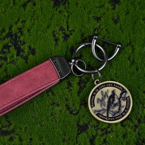 May include: A burgundy leather keychain with a metal clasp and a round pendant. The pendant features a bird design and the text "Destiny is in your own hands."