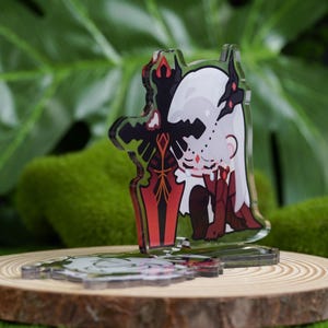 K&ouml;nnte beinhalten: Ein klarer Acryl-Anh&auml;nger mit einer Cartoon-Figur mit wei&szlig;en Haaren und roten Akzenten, die ein rotes und schwarzes Schwert h&auml;lt. Der Anh&auml;nger wird auf einer Holzscheibe mit gr&uuml;nem Hintergrund pr&auml;sentiert.