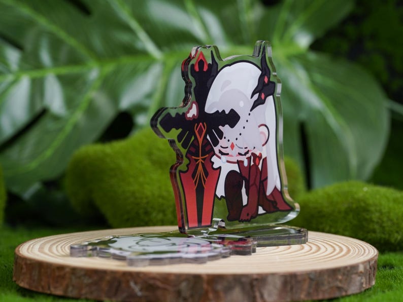 K&ouml;nnte beinhalten: Ein klarer Acryl-Anh&auml;nger mit einer Cartoon-Figur mit wei&szlig;en Haaren und roten Akzenten, die ein rotes und schwarzes Schwert h&auml;lt. Der Anh&auml;nger wird auf einer Holzscheibe mit gr&uuml;nem Hintergrund pr&auml;sentiert.