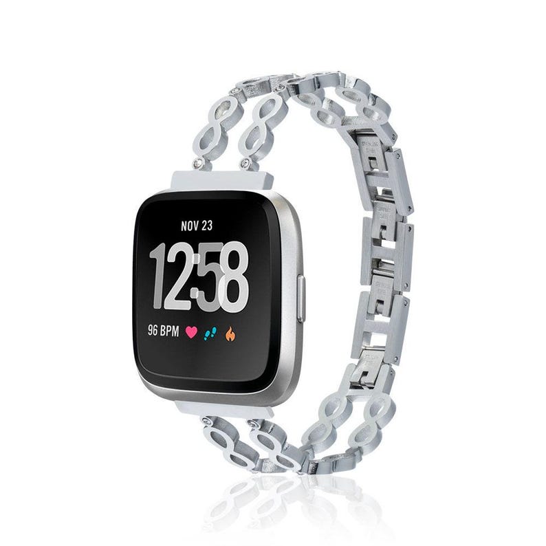 May include: A silver smartwatch with a black screen displaying the time as 12:58, date as Nov 23, and a heart rate of 96 BPM. The watch has a silver band with an infinity loop design.