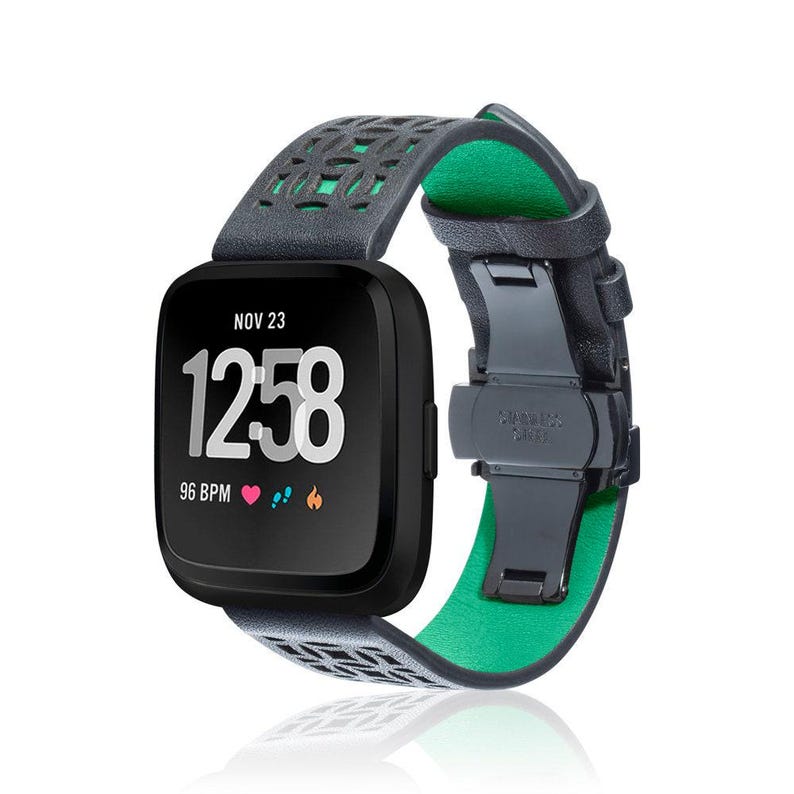 K&ouml;nnte beinhalten: Schwarze Smartwatch mit grauem, gemustertem Armband und gr&uuml;ner Innenseite. Das Zifferblatt zeigt die Uhrzeit 12:58, das Datum 23. November und eine Herzfrequenz von 96 BPM an. Das Armband hat einen Edelstahlverschluss.