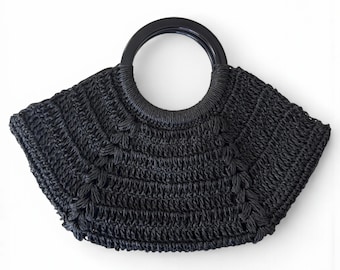 Könnte beinhalten: Eine schwarze gewebte Handtasche mit einem kreisförmigen Griff. Die Tasche hat eine fächerartige Form und besteht aus einem strukturierten Material. Der Griff ist von einfarbiger schwarzer Farbe. Die Tasche ist zum Tragen von Gegenständen konzipiert und hat einen stilvollen, modernen Look.