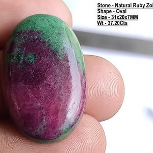 Op de afbeelding: Een ovaalvormige natuurlijke robijn-zoisiet edelsteen met een glad, gepolijst oppervlak met diepe magenta en levendige groene kleurvlekken. De steen meet 31x20x7mm en weegt 37,20 karaat, zoals aangegeven door de tekst op de afbeelding.
