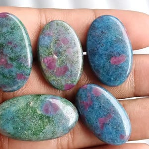May include: Five oval-shaped gemstones with a polished finish. The stones feature a mix of colors, including teal, green, and red. The gemstones are smooth and have a natural, organic appearance. These stones are suitable for jewelry making.