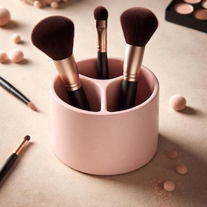 Puede incluir: Un soporte rosa claro para brochas de maquillaje con tres compartimentos, que contiene varias brochas de maquillaje con mangos negros y detalles en oro rosa. También se ven brochas de maquillaje adicionales, colorete y sombra de ojos.